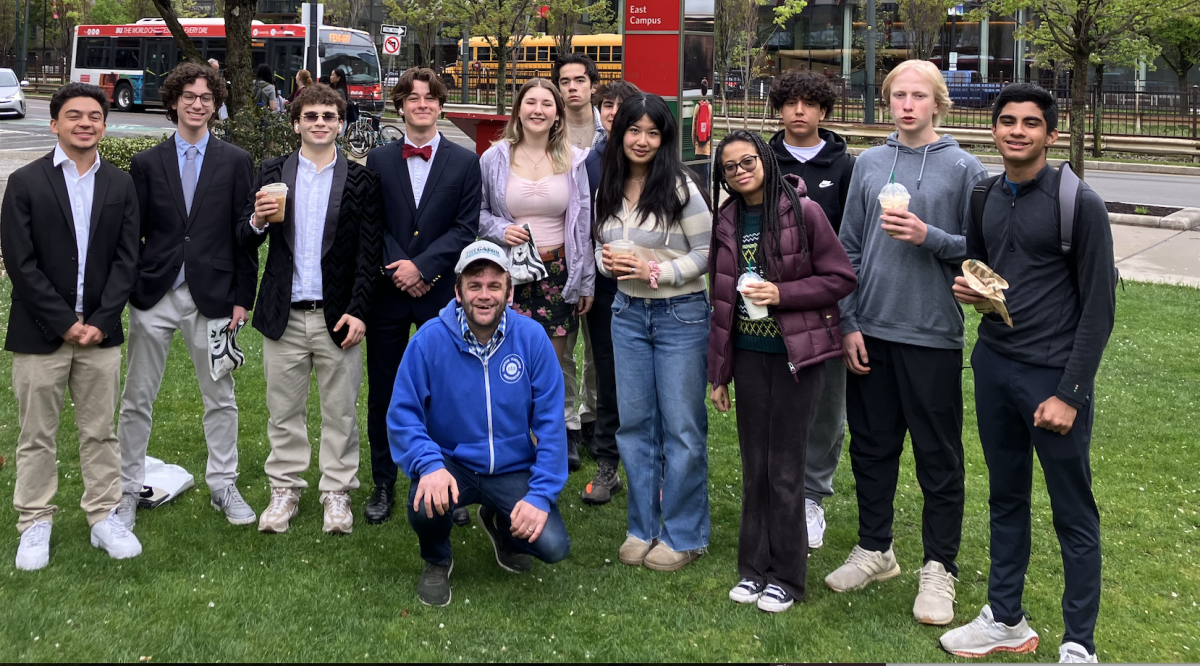 The 2024-25 staff gathers in front of Boston University before the spring New England Scholastic Press Association conference. From left: Jackson Tarbox '26, Tavio Mares-Van Praag '27, Gabe Cohen '26, Andrew Flint '26, Stella Bowman '28, Clive Owens '28, Charlie Rossi '28, Mary Wang '26, Livvy Avignon '26, Leo Latino '28, Kingston Woolley '28, and Rohan Muni '28. Center: Adviser David Cutler. Not pictured: Amelia Bowman '25, Jack Malloy '25, Chloe Rose Scolnick '25, and Rachael Rosenberg '27. 
